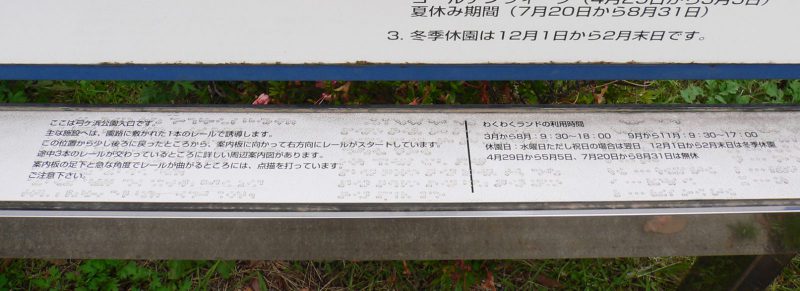 写真：点字の案内。「主な施設へは園路に敷かれた一本のレールで誘導します」などと書かれている