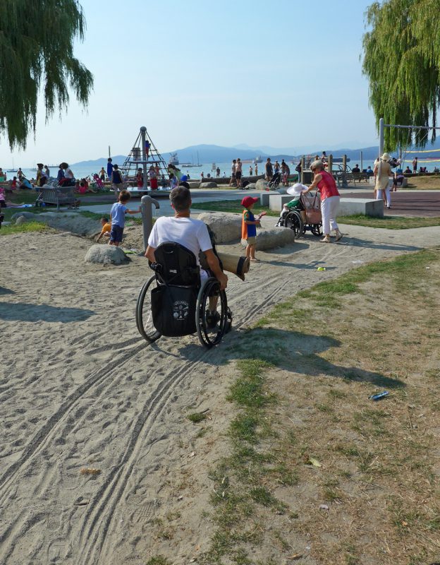 写真：砂の積もった園路を進む車いすユーザーたち