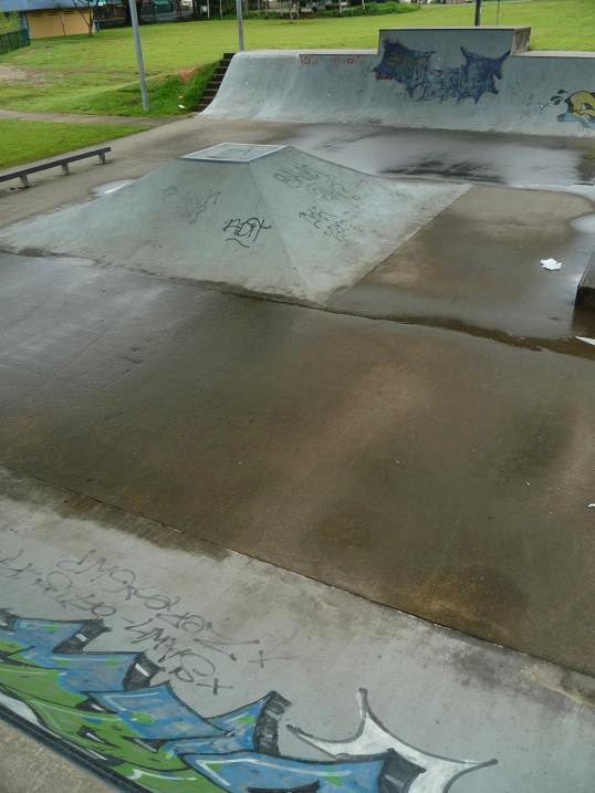 写真：両側にはカーブしたジャンプ台、中央にバンクなどが設けられたスケートパーク。舗装面にはスプレーで描かれたグラフィティも