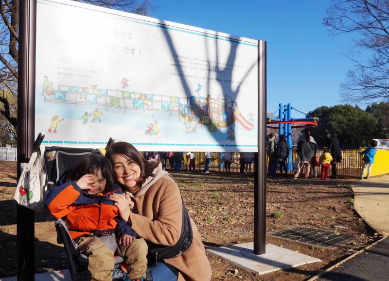 写真：「みんなのひろば」の看板の前で笑顔の龍円さんとニコくん