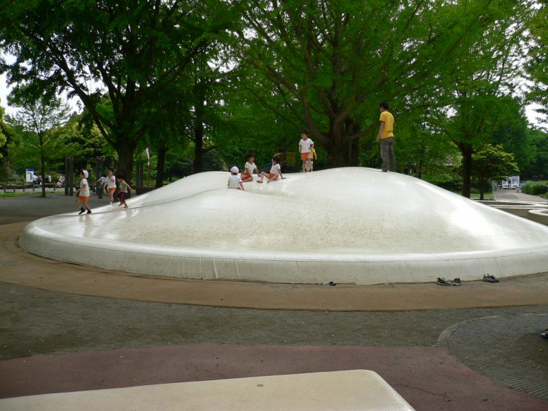 写真：白い膜状のトランポリン「ふわふわドーム」。上では幼稚園児7～8人と一人の少年が遊んでいる