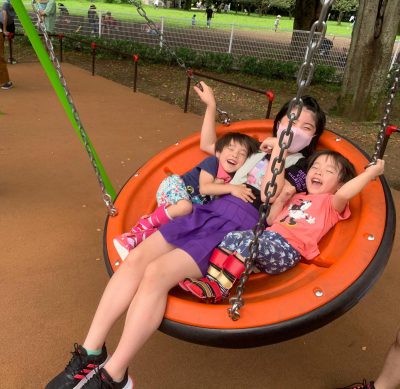 写真:皿型ブランコを楽しむ、下肢装具を付けた双子の男の子とお姉ちゃん