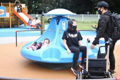 写真:回転遊具を回すお父さんと、笑顔のおねえちゃんと弟