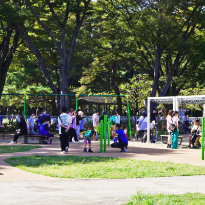 写真：花の形をした伝声管にしゃがんで話しかける男性と、少し低い別の伝声管に耳を傾けている男の子。