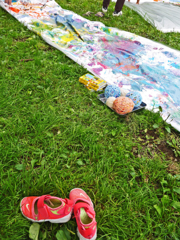 写真：芝地に長々と敷かれた帆布のキャンバスが色とりどりに塗られている。