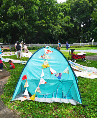 写真：休憩用の簡易テント。子どもたちが自由に塗った楽しげな旗で飾られている。