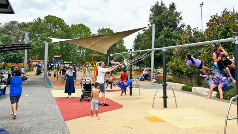 写真：子どもたちでいっぱいのブランコエリア。皿形ブランコには4人の女の子が乗り、立位や座位で力を合わせ勢いよくこいでいる。