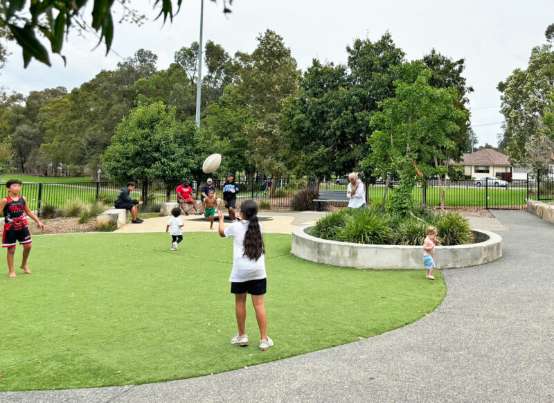 写真：ボールを投げ合う2人の子ども。近くをよちよち歩きの子が通りかかる。