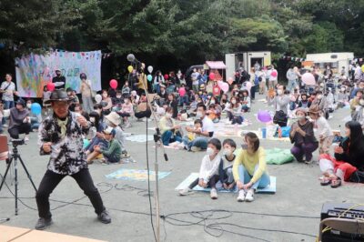 写真:屋外の仮説ステージでの演奏を鑑賞する多くの家族連れ。