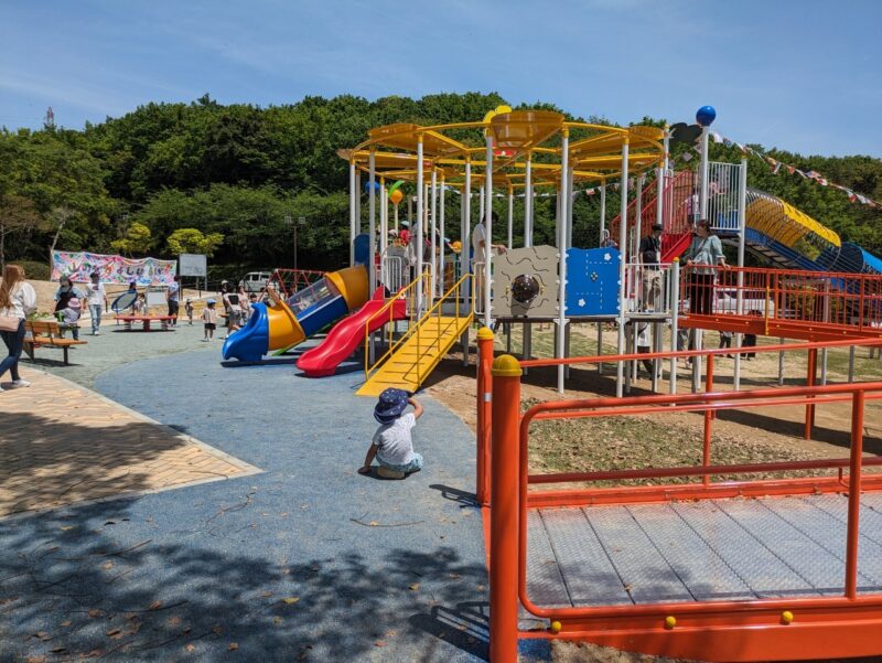 写真:複合遊具の円形デッキの周囲に、スロープや滑り台やプレイパネル。