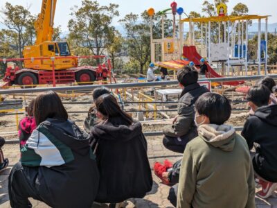 写真:クレーンで遊具を組み立てる様子を見学する子どもたち。