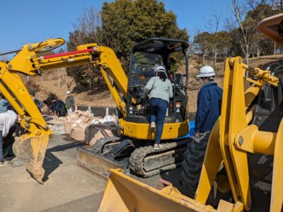 写真:ショベルカーの運転席に乗り込む女の子。
