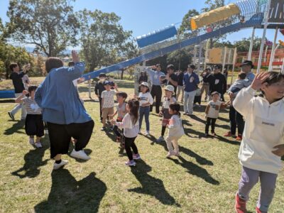 写真:芝生広場で大人の動きに合わせて踊る子どもたち。