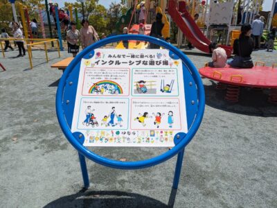 写真:遊び場の看板。「みんなで一緒に遊べるインクルーシブな遊び場」の文字。