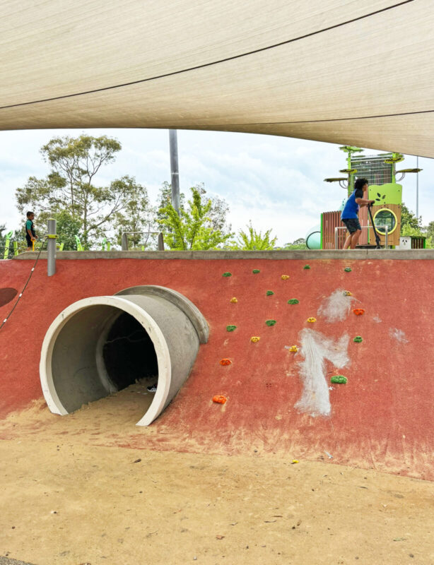 真：大きなトンネルの入り口。左右の斜面にはボルダリングのホールドやロープ。