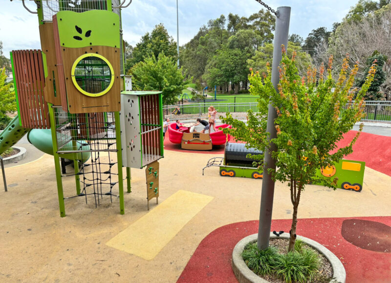 写真：同じく大きな複合遊具や大型シーソー。家族6人が力を合わせてシーソーを揺らしている。