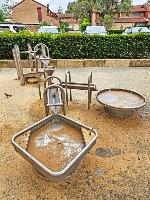 写真：筧の水遊び場。水盤や地面は砂まみれで水を流した跡がある。